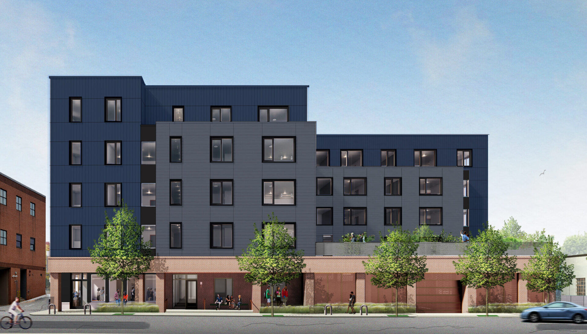 Dark blue and smoky grey 5 story building with rosy brick first floor and lots of windows, with trees along its sidewalk