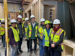 7 people in hard hats stand in front of wooden framed structure
