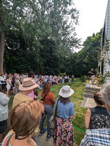 large crowd outside facing housing unit as Select Board and Housing Trust member Eric Helmuth speaks.