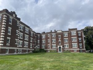 L shaped brick building with white trim built in the 1920's with large lawn in front of it