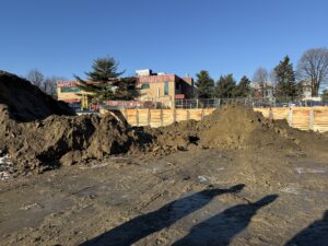 view of construction site with flat area of dirt, dirt piles, and wooden lagging in background