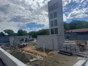 view of construction site. Dirt throughout, with concrete wall around and 5-story elevator shaft, plus two 2-story concrete block stairwells.