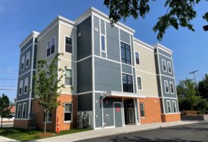 three story building on a sunny day with a clear blue skey. The building is blue, cream and rust colored.